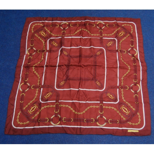 136 - Must de Cartier silk scarf on a claret ground, 83cm x 79.5cm, with original sleeve.