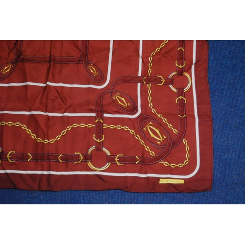 136 - Must de Cartier silk scarf on a claret ground, 83cm x 79.5cm, with original sleeve.