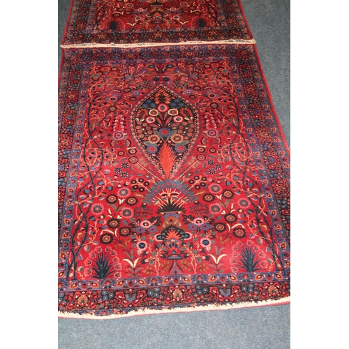 583 - Pair of red ground Eastern rugs, the field decorated with a vase of flowers flanked by multiple bord... 