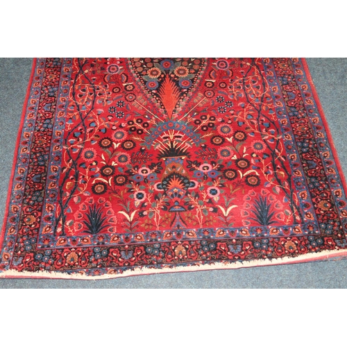 583 - Pair of red ground Eastern rugs, the field decorated with a vase of flowers flanked by multiple bord... 