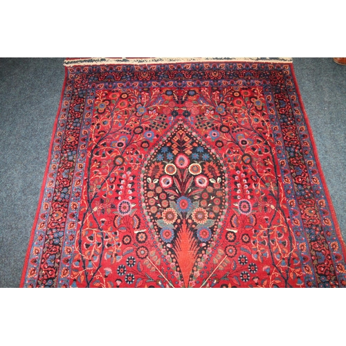 583 - Pair of red ground Eastern rugs, the field decorated with a vase of flowers flanked by multiple bord... 