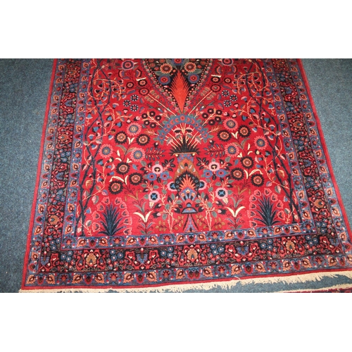 583 - Pair of red ground Eastern rugs, the field decorated with a vase of flowers flanked by multiple bord... 