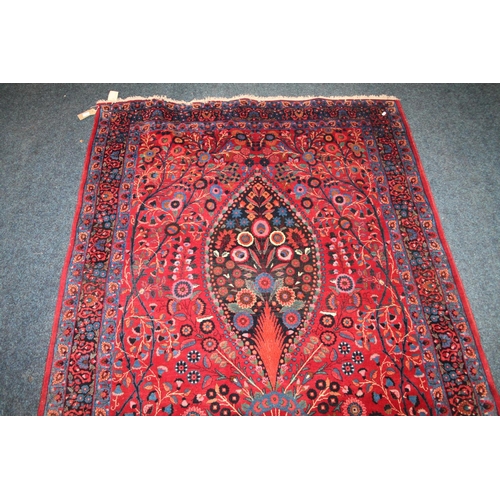 583 - Pair of red ground Eastern rugs, the field decorated with a vase of flowers flanked by multiple bord... 