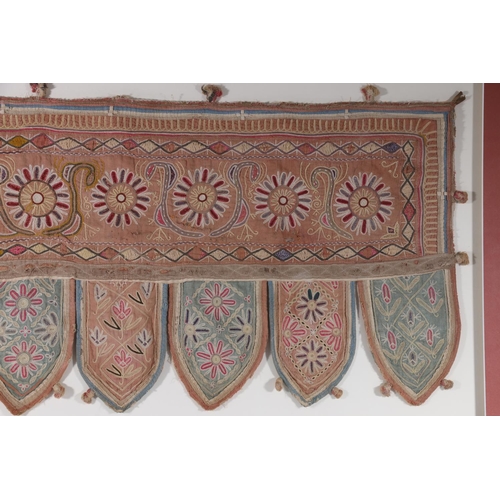 364 - An Indian hanging panel with floral embroidery, the main panel decorated with flowerheads with seven... 