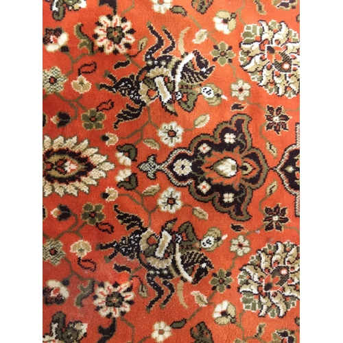 601 - Large wool rug, orange field decorated with hunting scenes with Arab figures on horseback chasing bi... 