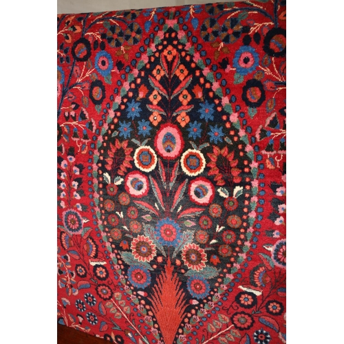 583 - Pair of red ground Eastern rugs, the field decorated with a vase of flowers flanked by multiple bord... 