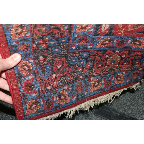 583 - Pair of red ground Eastern rugs, the field decorated with a vase of flowers flanked by multiple bord... 