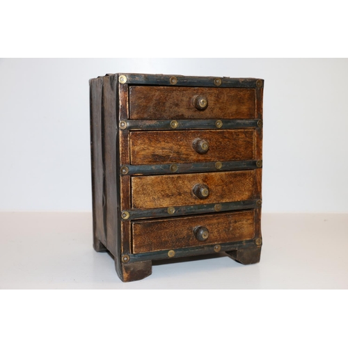 7 - North African metal bound wood miniature four drawer chest, 21cm tall.