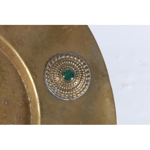 31 - Indian brass dish decorated with relief rings set with four coloured cabochons, 24cm diameter.