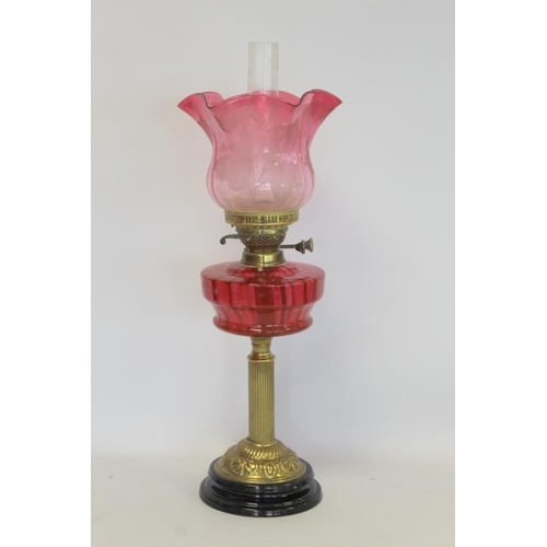 202 - Victorian oil lamp, the cranberry glass reservoir with internal ribbing on brass reeded column and b... 