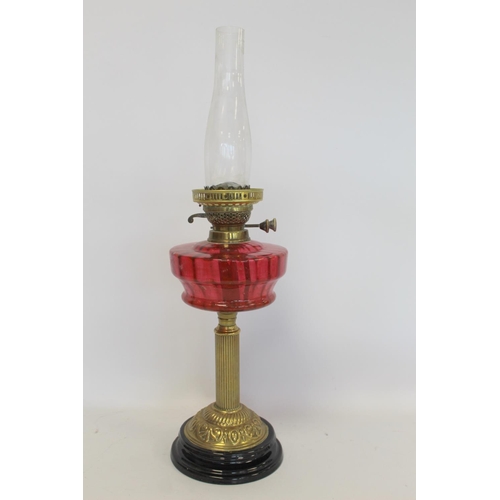 202 - Victorian oil lamp, the cranberry glass reservoir with internal ribbing on brass reeded column and b... 