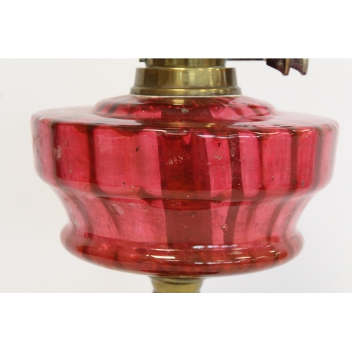 202 - Victorian oil lamp, the cranberry glass reservoir with internal ribbing on brass reeded column and b... 