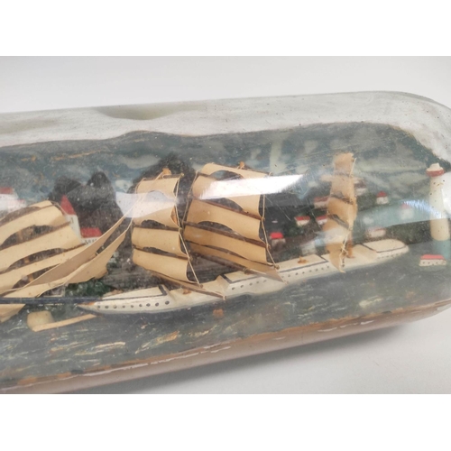 223 - Antique folk art naive ship in a bottle depicting a clipper ship against a harbour background.