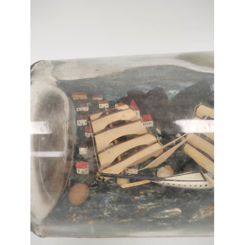 223 - Antique folk art naive ship in a bottle depicting a clipper ship against a harbour background.