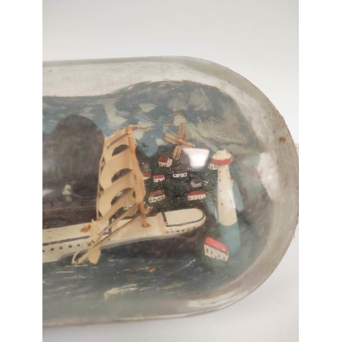 223 - Antique folk art naive ship in a bottle depicting a clipper ship against a harbour background.