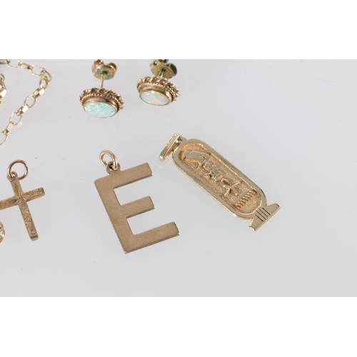 200W - 9ct gold pedant of ingot form with Egyptian hieroglyphs, a 9ct gold 'E' pendant, a 9ct gold crucifix... 