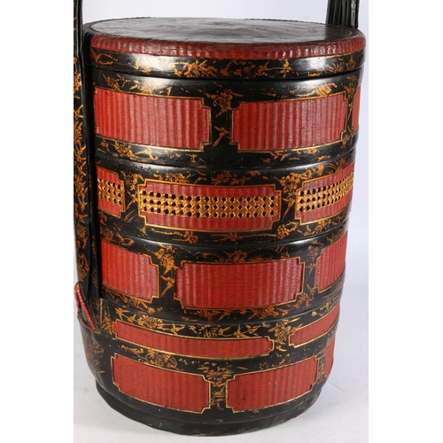 493 - Chinese wicker wedding basket with black lacquer and gilt decoration and red ground, 60cm tall.