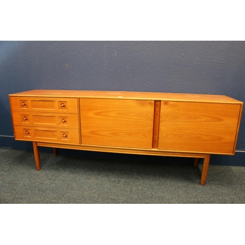 567 - Mid-century teak sideboard, having three drawers and two panel doors, raised on turned supports, in ... 