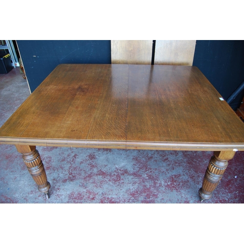 364 - Edwardian oak extending dining table with two additional leaves, on carved baluster supports and cas... 