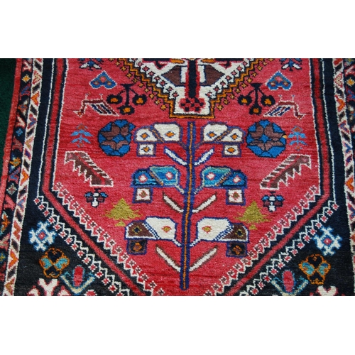 302 - Qashqai hand-knotted runner decorated with four geometric medallions on red ground, 230cm x 136cm.