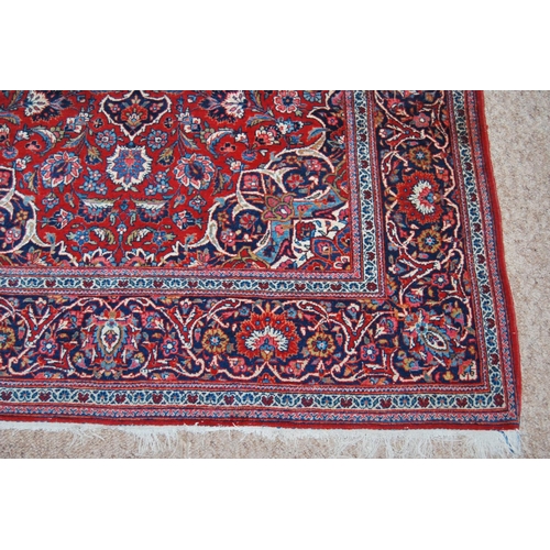 303 - Persian Kashan rug decorated with all over floral swags on a red ground, 224cm x 136.5cm.