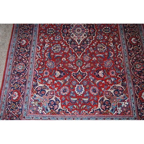 303 - Persian Kashan rug decorated with all over floral swags on a red ground, 224cm x 136.5cm.