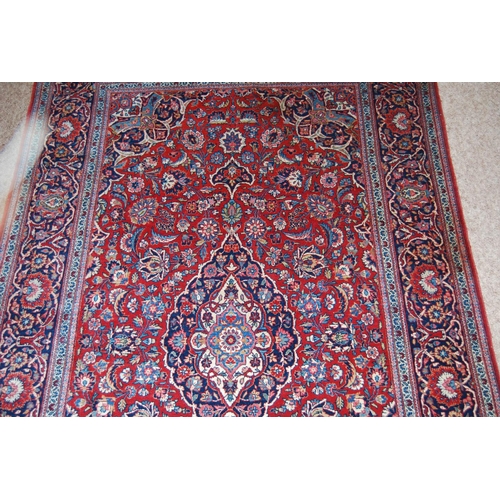 303 - Persian Kashan rug decorated with all over floral swags on a red ground, 224cm x 136.5cm.