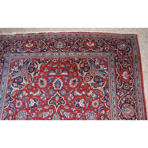 303 - Persian Kashan rug decorated with all over floral swags on a red ground, 224cm x 136.5cm.