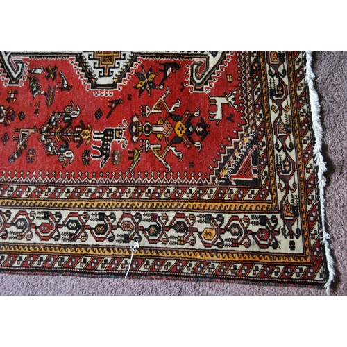 306 - Persian rug decorated with all over geometric medallions and motifs on a red ground with cream borde... 