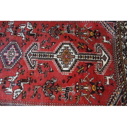 306 - Persian rug decorated with all over geometric medallions and motifs on a red ground with cream borde... 