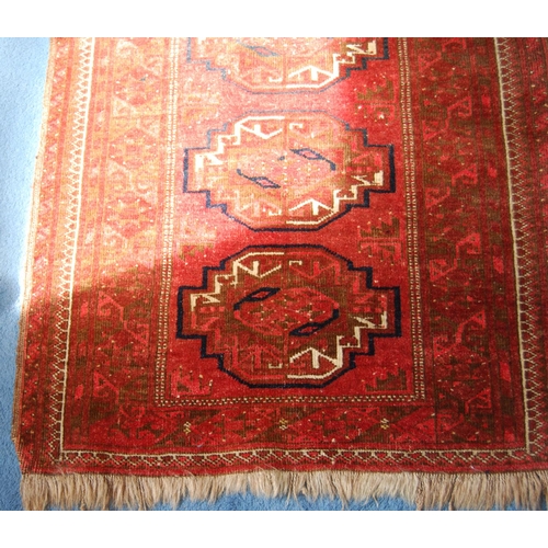 307 - Bokhara rug decorated with six geometric medallions on a red ground, 170cm x 86cm.