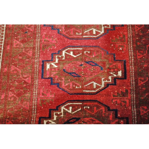 307 - Bokhara rug decorated with six geometric medallions on a red ground, 170cm x 86cm.