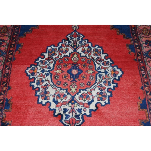 308 - Dosemealti hand-knotted rug decorated with a large geometric medallion to the centre, on a red groun... 