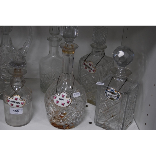 199 - Eight crystal and cut glass decanters, some with ceramic spirit labels (one shelf).