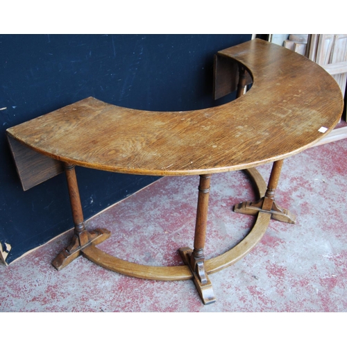 385 - Oak reading/library table of curved form with extending drop flaps, on turned supports, label to the... 