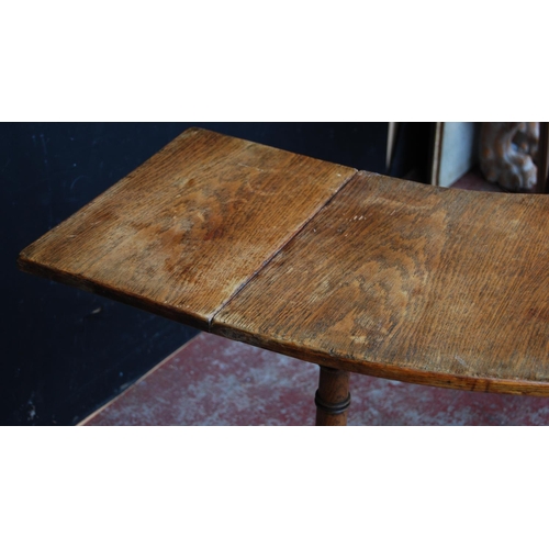 385 - Oak reading/library table of curved form with extending drop flaps, on turned supports, label to the... 