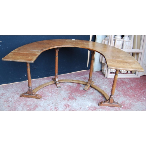 385 - Oak reading/library table of curved form with extending drop flaps, on turned supports, label to the... 