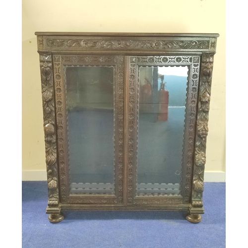 497 - Victorian stained oak glazed bookcase with twin doors, carved with mask heads , fruit, flora and fol... 