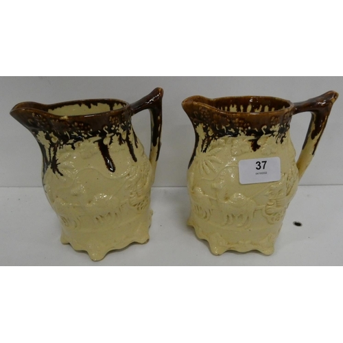 37 - Pair of brown and cream treacle glazed jugs moulded with camels drawing carriages.