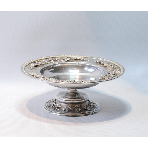 127 - Silver small tazza of high quality with a band of fruiting vines in high relief upon matting, upon s... 