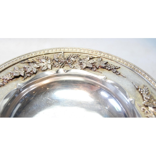 127 - Silver small tazza of high quality with a band of fruiting vines in high relief upon matting, upon s... 