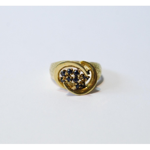 77 - 18ct gold ring with double spiral enclosing eleven sapphire collets, 1974, size M, 5g.