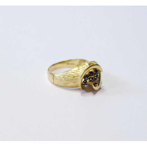 77 - 18ct gold ring with double spiral enclosing eleven sapphire collets, 1974, size M, 5g.