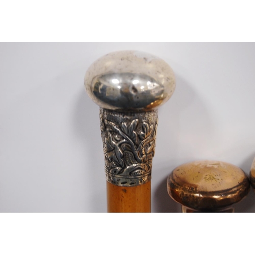 203 - Four walking sticks to include three ebonised sticks with silver, rose-coloured, quartz-style pommel... 