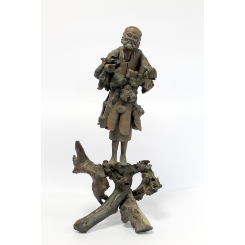 338 - 19th or early 20th century Oriental carved root wood figure of a peddler holding a shoe, the face wi... 