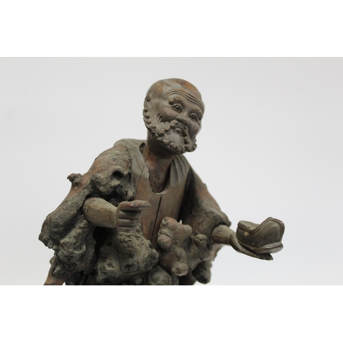 338 - 19th or early 20th century Oriental carved root wood figure of a peddler holding a shoe, the face wi... 