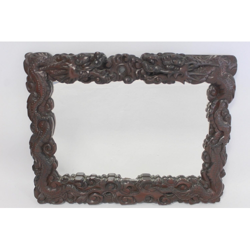 342 - Late 19th or early 20th century Chinese carved hardwood wall mirror, the frame in the form of two sc... 