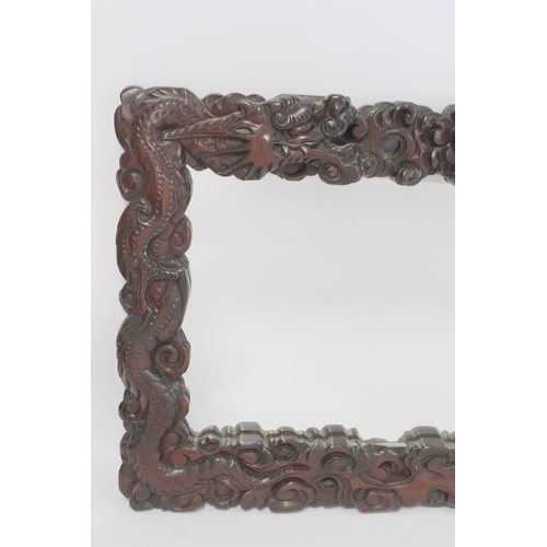 342 - Late 19th or early 20th century Chinese carved hardwood wall mirror, the frame in the form of two sc... 