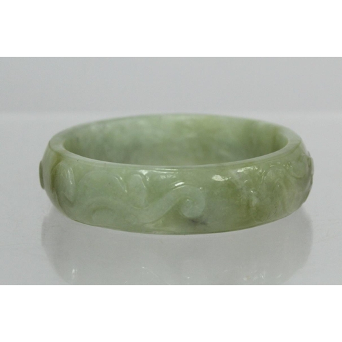 368 - Chinese pale green mottled jade bangle with relief carved decoration of Chilong, approx. 7.5cm diam.... 