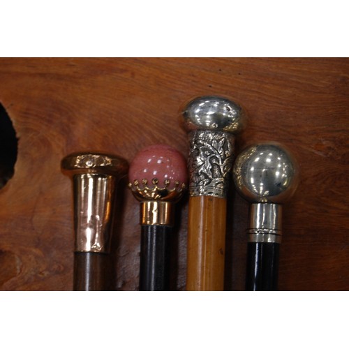 203 - Four walking sticks to include three ebonised sticks with silver, rose-coloured, quartz-style pommel... 